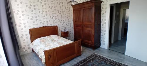 een slaapkamer met een bed en een houten kast bij appartement 2 chambres in Baccarat