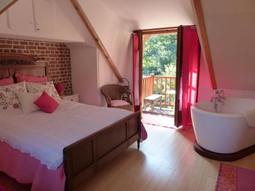 1 dormitorio con cama, bañera y ventana en La Flore De Lys en Saint-Jouin-Bruneval