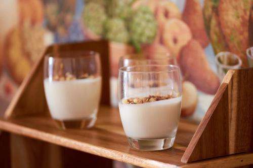 two glasses of milk sitting on a wooden shelf at Hotel Gabbiano - Garda Lake Collection in Garda