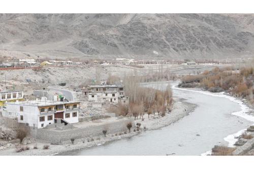 uitzicht op een rivier met gebouwen en een stad bij Indus Retreat in Chimre