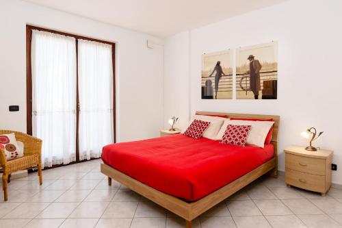 a white bedroom with a red bed and a chair at Casa Dany - Alba - Family Apartment in Guarene