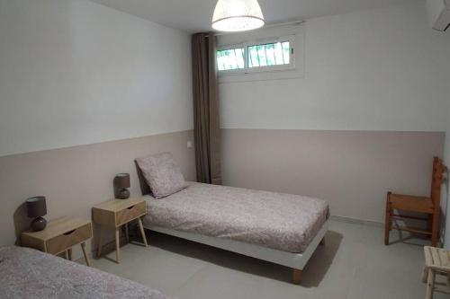 une chambre avec deux lits et une chaise et une fenêtre dans l'établissement Charmant rez de villa, et sa terrasse à Ajaccio, à Ajaccio