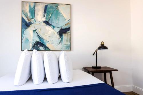a bedroom with a bed with white pillows and a painting at 1BR Luxury Apartment Peabody - Unit #606 in Peabody