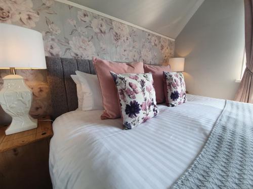 a bed with pink and white pillows on it at Plas Dinas Country House in Caernarfon