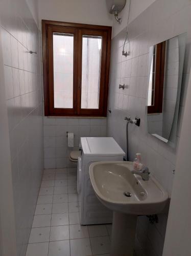 Baño blanco con lavabo y aseo en Casa Bianca Luce, en Torre Santa Susanna