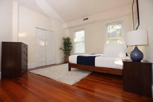 a bedroom with a bed and a dresser with a lamp at Stylish Apartment in Malden 20 Min from Boston #2 in Malden