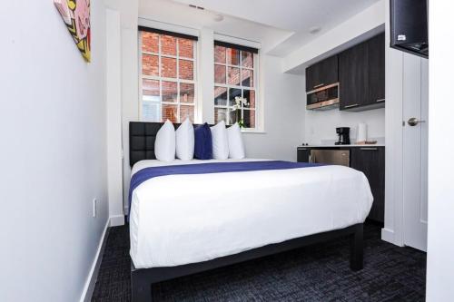 a bedroom with a large white bed with blue pillows at Modern Studio in Historic Boston - Garden Unit #4 in Boston