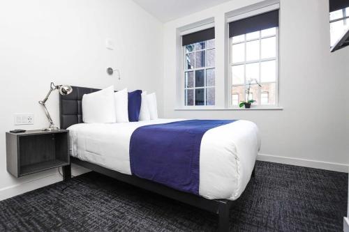 a bedroom with a large bed and two windows at Stylish Studio in Fenway Neighborhood - Unit #306 in Boston