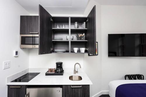 a kitchen with black cabinets and a sink and a bed at Stylish Studio in Historic Boston - Unit #404 in Boston
