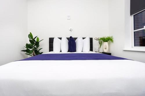 una camera da letto con un grande letto con lenzuola blu e cuscini bianchi di Modern Studio in Historic Boston - Unit #101 a Boston
