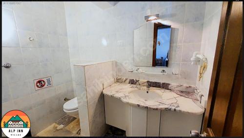 a bathroom with a sink and a mirror and a toilet at Alp inn Butik Apart ve Restoran in Marmaris