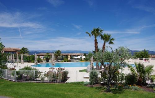 une piscine avec une clôture et des palmiers dans l'établissement Villa Domaine du golf de Roquebrune, à Roquebrune-sur Argens