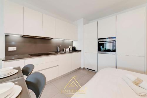 a kitchen with white cabinets and a table and chairs at Rame Loft per 4 Persone a Bellinzona -By EasyLife Swiss in Bellinzona