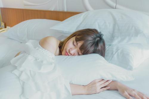 uma rapariga a dormir na cama com a cabeça numa almofada em G Hua Hin Resort & Mall em Hua Hin