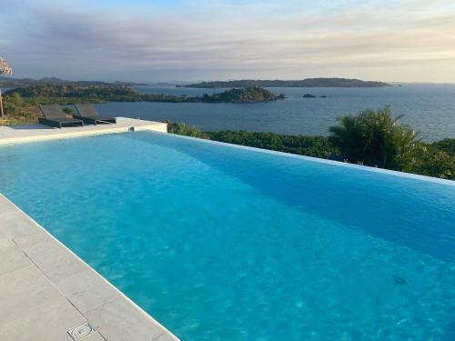 een groot zwembad met uitzicht op het water bij Villa luxueuse avec une vue extraordinaire in Andilana