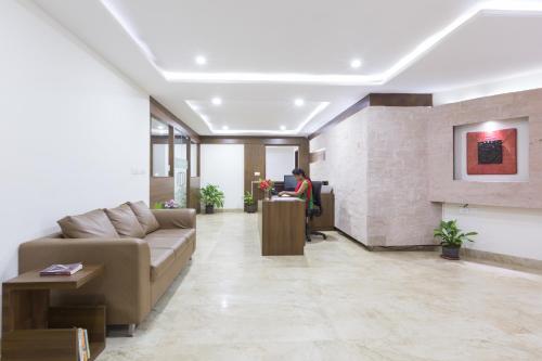 a lobby with a couch and a person standing at a counter at Sanctum Suites BEL Road Bangalore in Bangalore