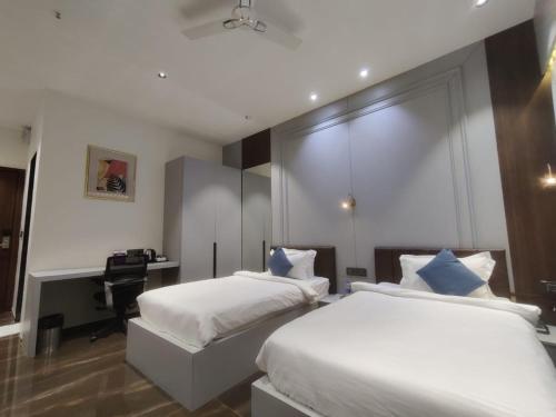 a bedroom with two beds and a desk in it at VITS Jamnagar in Jamnagar
