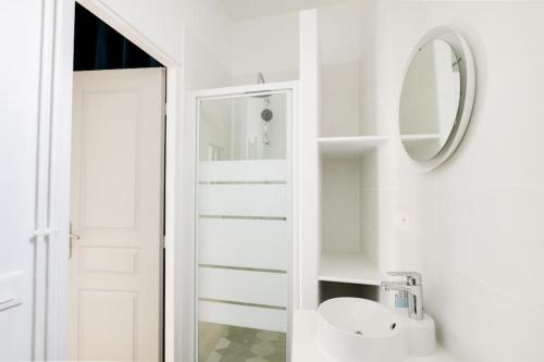uma casa de banho branca com um lavatório e um espelho em Aux Clefs des Sacres - Le Chabaud 5 em Reims