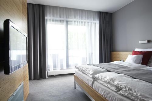 a bedroom with a bed and a large window at Wellness Hotel ABÁCIE in Nový Jičín