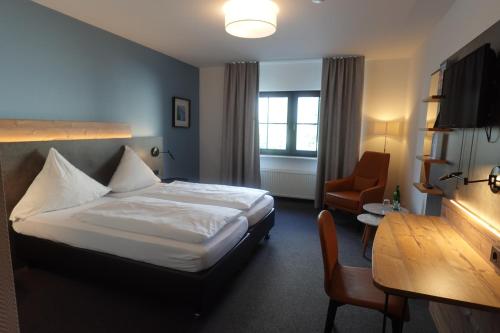 een hotelkamer met een bed en een stoel bij Hotel & Weinhaus Zum Schwarzen Bären in Koblenz