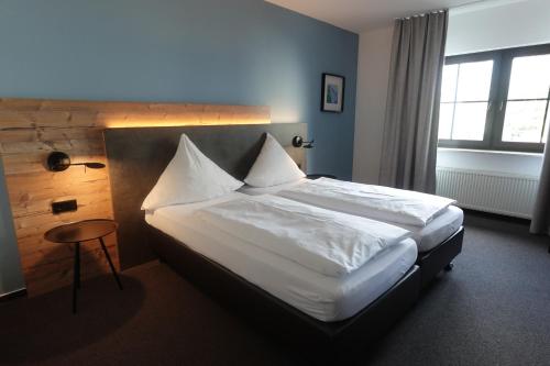 a bedroom with a bed with white sheets and a table at Hotel & Weinhaus Zum Schwarzen Bären in Koblenz