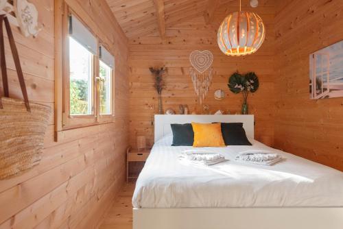 ザントフォールトにあるThe Sea Lodgeの木製の部屋に白いベッドが備わるベッドルーム1室