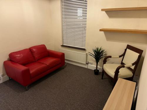 a living room with a red couch and a chair at Mill Hill Stays in Derby