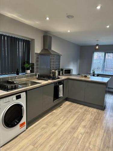 a large kitchen with a washer and dryer in it at Lux 3 Bed 10 mins from Centre - Parking & Netflix in Manchester