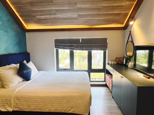 a bedroom with a bed and a desk with a mirror at De La Sol Villa Dalat in Da Lat
