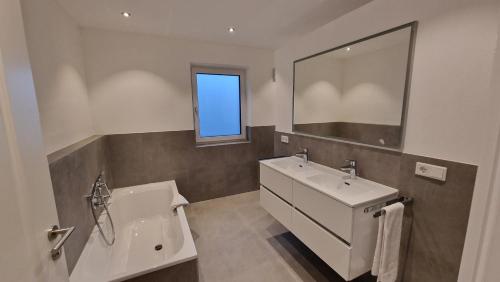 La salle de bains est pourvue d'un lavabo, de toilettes et d'un miroir. dans l'établissement Ferienhaus Sisi - Moderner Neubau im Grünen, nahe See, S-Bahn und mit E-Ladesäule, à Pöcking