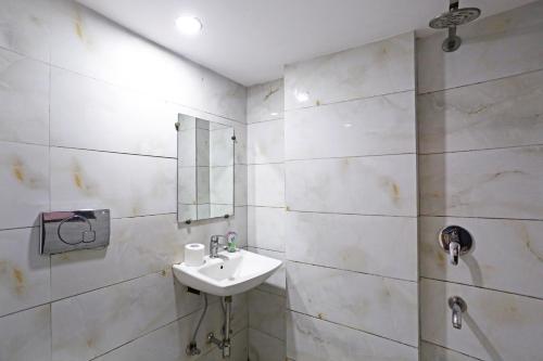 ein weißes Badezimmer mit einem Waschbecken und einem Spiegel in der Unterkunft Ratandeep International in Neu-Delhi
