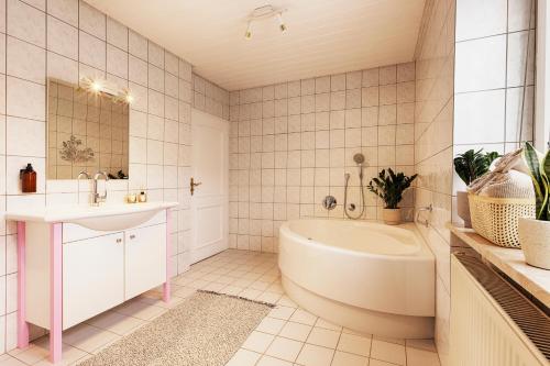 a white bathroom with a tub and a sink at Fewos am Main mit Dachterrasse & Fahrradgarage - by homekeepers in Ochsenfurt