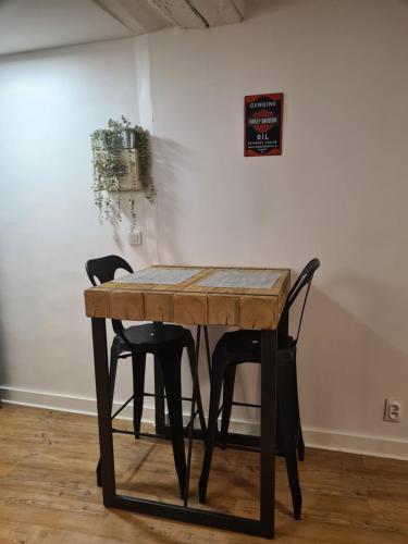 une table en bois entourée de deux chaises noires dans l'établissement Studio Bon pasteur hyper centre Aix, à Aix-en-Provence