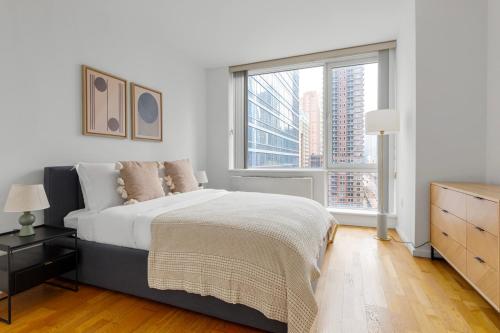 a white bedroom with a bed and a large window at Blueground Hells Kitchen gym elev nr museum NYC-1434 in New York