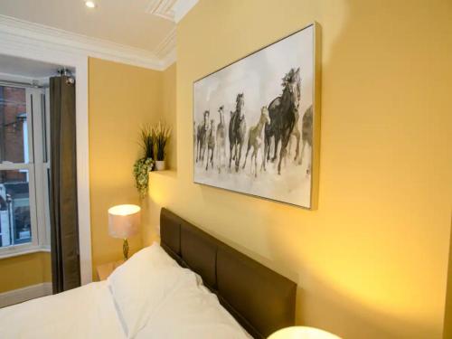 a bedroom with a picture of horses on the wall at Pass the Keys The Sunny Room at Tavmar Apartments in Lincoln