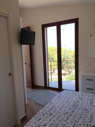 a bedroom with a bed and a sliding glass door at Addisa Locazione Breve in Castellammare del Golfo