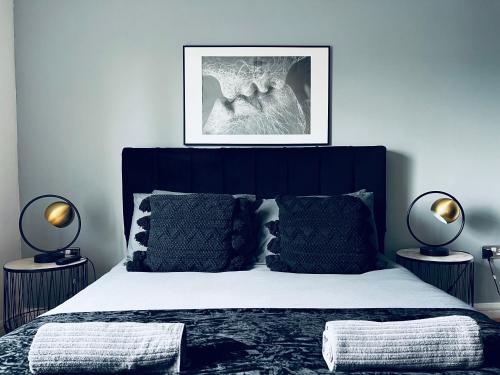 a bedroom with a bed with a black headboard and two lamps at Penthouse Birmingham City View in Birmingham