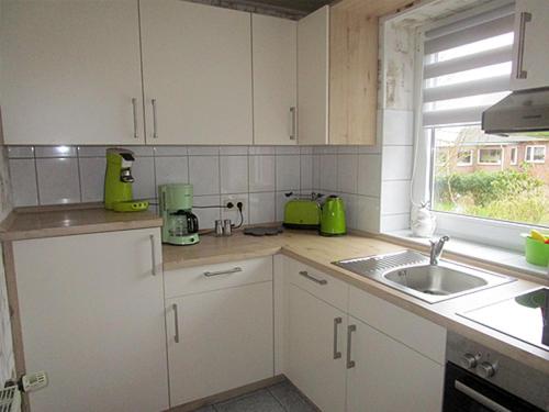 a kitchen with white cabinets and a sink and a window at Ferienwohnung Uthlande in Langeneß