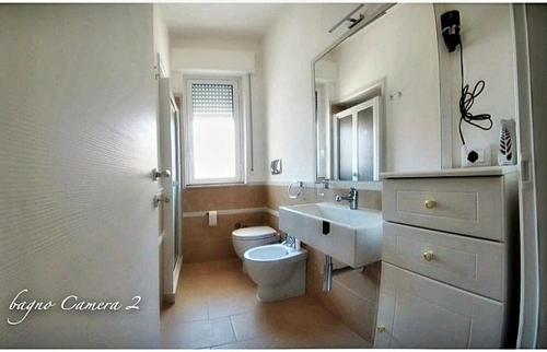 a white bathroom with a toilet and a sink at Casa Tramonto sull' Isola in Marzamemi