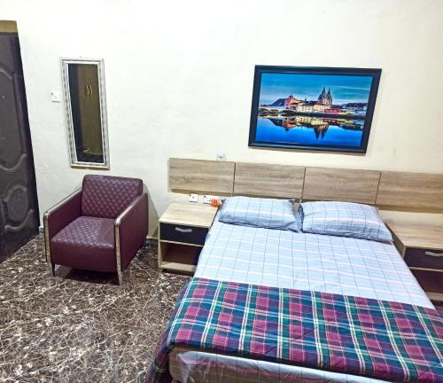ein Hotelzimmer mit einem Bett und einem Stuhl in der Unterkunft Bravo Apartment, Awka in Akwa