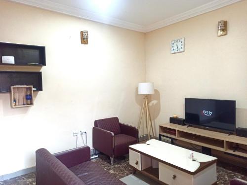 ein Wohnzimmer mit 2 Stühlen und einem TV in der Unterkunft Bravo Apartment, Awka in Akwa
