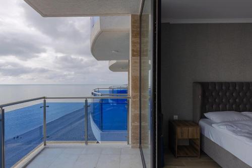 a balcony with a bed and a view of the ocean at Panorama Kvariati beach in Kvariati