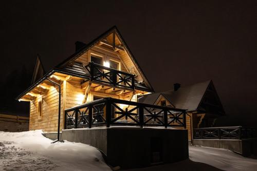 una cabaña de madera con una luz en la nieve en Domek pod lasem-Orawskie Ranczo, en Harkabuz
