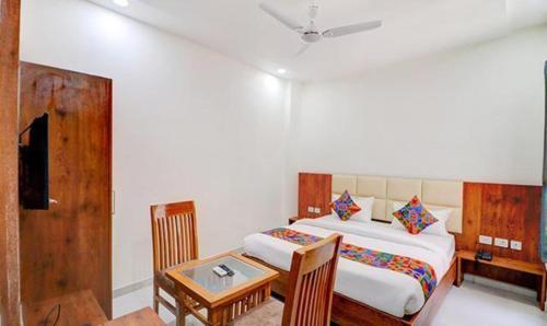 a bedroom with a bed and a desk and a table at FabExpress Pravi Inn in Lucknow