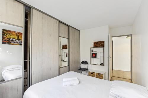 ein Schlafzimmer mit einem weißen Bett und zwei Spiegeln in der Unterkunft Chic and confortable apart near stade de France in Saint-Denis