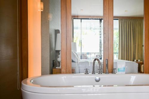 a bath tub in a bathroom with a window at Dune Hua Hin Hotel in Hua Hin