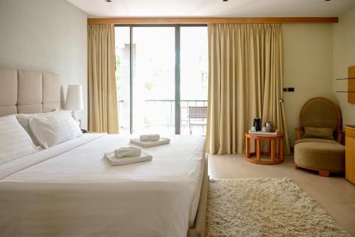 a bedroom with a large white bed and a chair at Dune Hua Hin Hotel in Hua Hin