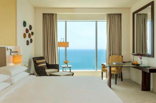 Habitación de hotel con cama, escritorio y ventana grande. en Hyatt Regency Cartagena en Cartagena de Indias