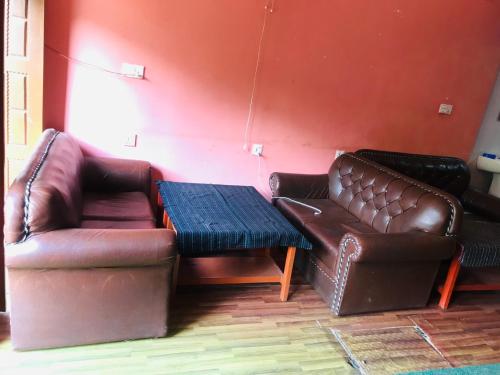 a living room with two leather couches and a table at Shristi Hotel & Lodge in Bandīpur