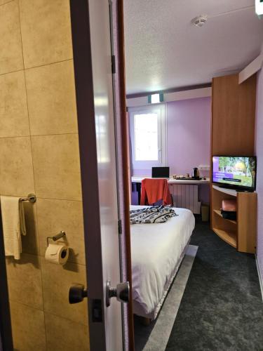 Kleines Zimmer mit einem Bett und einem TV in der Unterkunft Hotel Bonanite in Villers-Cotterêts